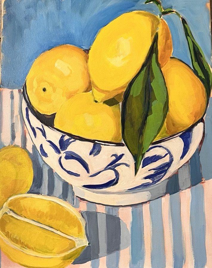 Bright yellow lemons piled in a blue-and-white painted bowl on a striped pink and blue cloth.